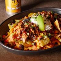 Brisket Nachos · Tender and juicy slow-smoked brisket piled high on a bed of tortilla chips and topped with B...