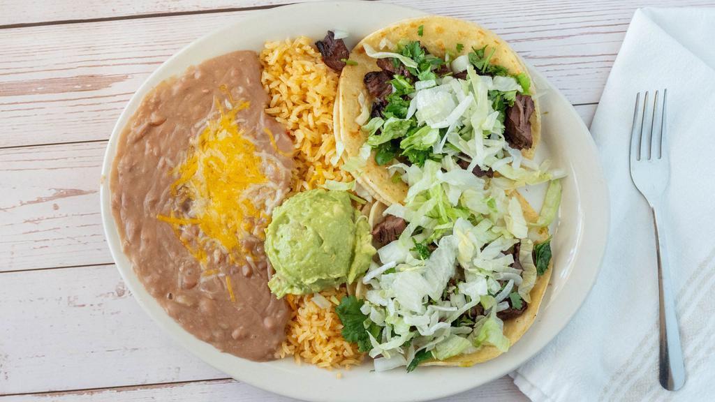Mexican Street Tacos · Two corn or flour tortilla tacos filled with fajita beef or fajita chicken. Topped with lettuce, onions, cilantro, salsa ranchera, and served with guacamole.