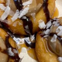 Sammy · Mini donuts coated in coconut topped with caramel, chocolate icing and chocolate syrup.
