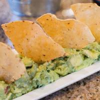 Guac And Chips · Bowl of avocado dip with diced tomato, onion, and cilantro.