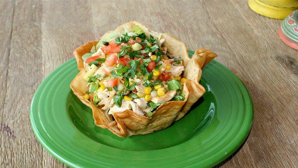 Honey Lime Chicken Salad · A flour tortilla bowl filled with lettuce then topped with seasoned grilled lime shredded chicken, corn, cilantro and pineapple salsa, served drizzled with honey lime dressing.