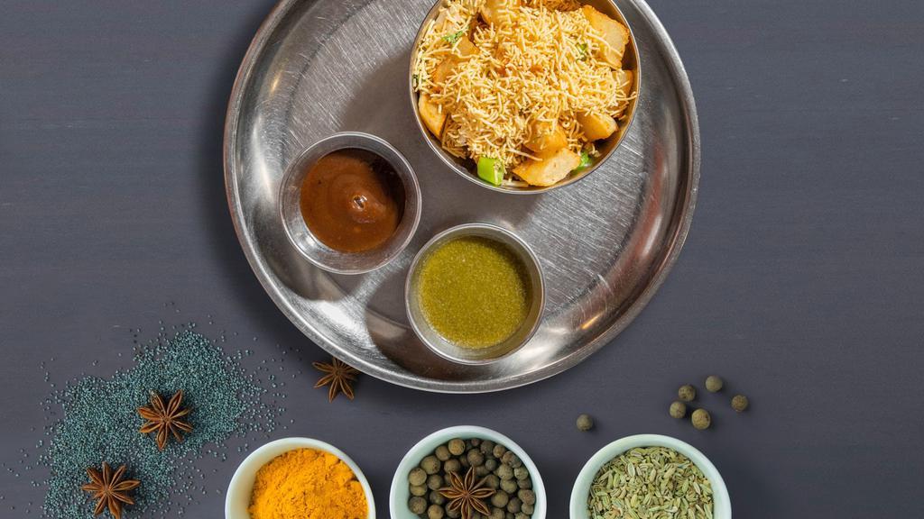 Aloo Tikki Madness · Aloo tikki or mashed potato patties sauteed in yogurt, chickpeas curry, nimki, chaat masala and bhujiya.