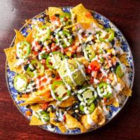 Smoked Chicken Nachos · Fresh fried corn chips dusted with secret spice smothered with white Cheddar sauce and shred...