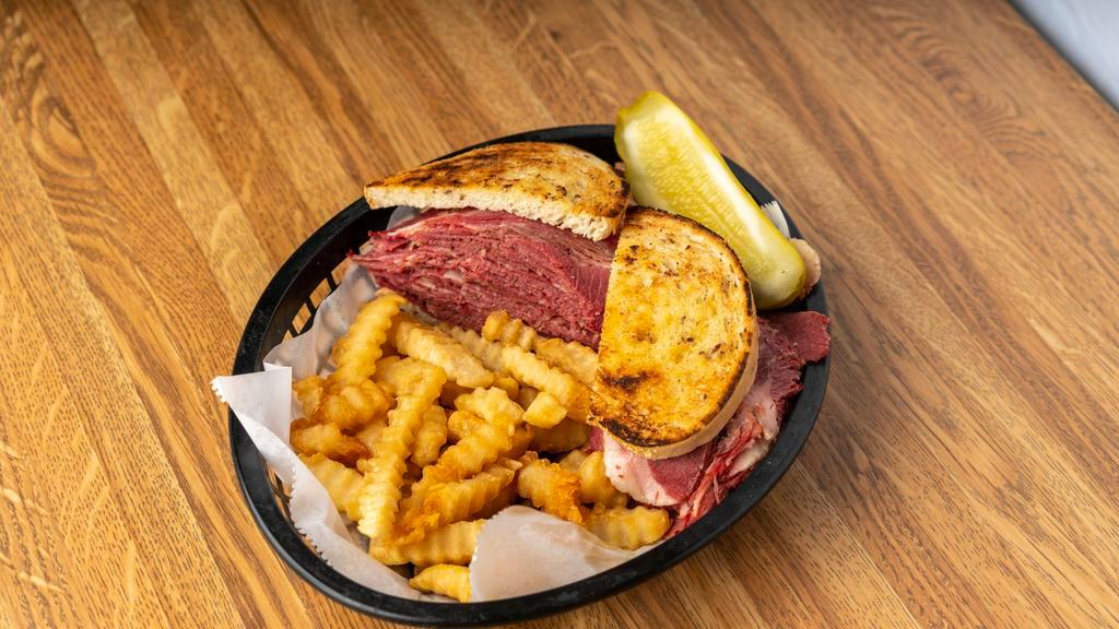 Corned Beef, Pickle & Fries · A tower of corned beef, topped with mustard, served on rye.