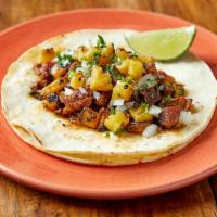 Al Pastor Taco · Achiote marinated pork shoulder with roasted pineapples. Topped with cilantro, and onion. Se...
