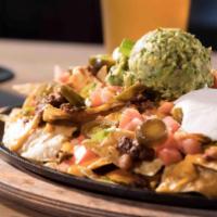 Loaded Nachos · Tortilla chips, chef-made chili, cheddar cheese sauce, jalapeños, tomatoes, sour cream, gree...