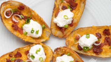 Potato Skins · Smothered with cheddar cheese, bacon, and onions, served with sour cream.