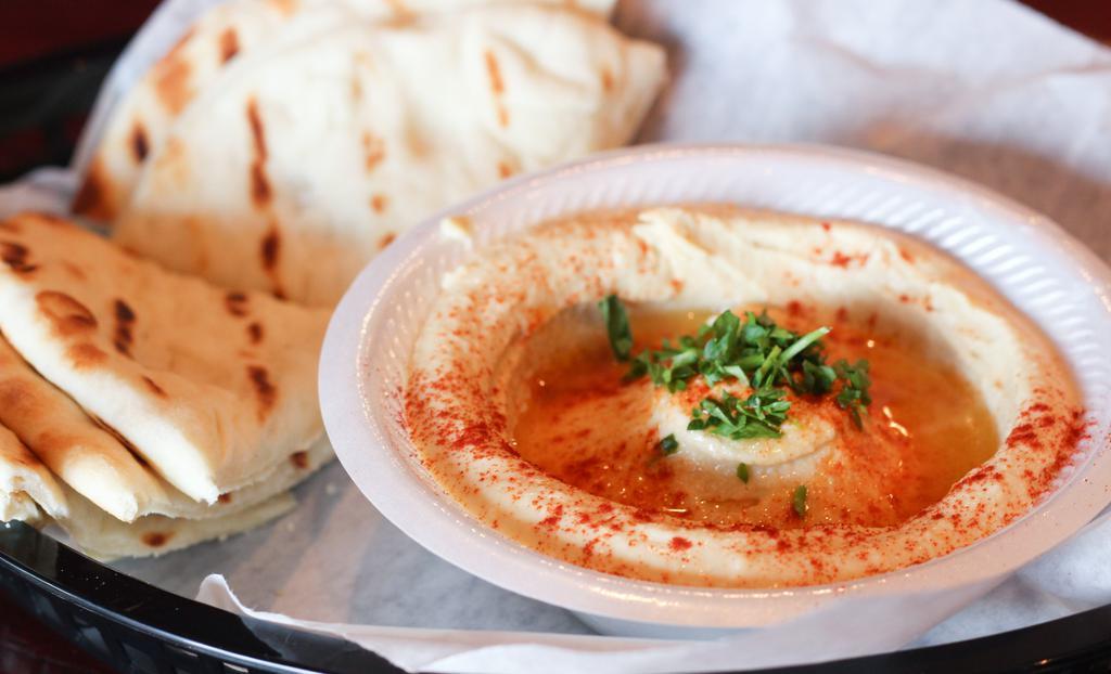 Hummus · Smooth dip of garbanzo beans, tahini sauce and garlic, topped with olive oil, served with two hot pita bread.