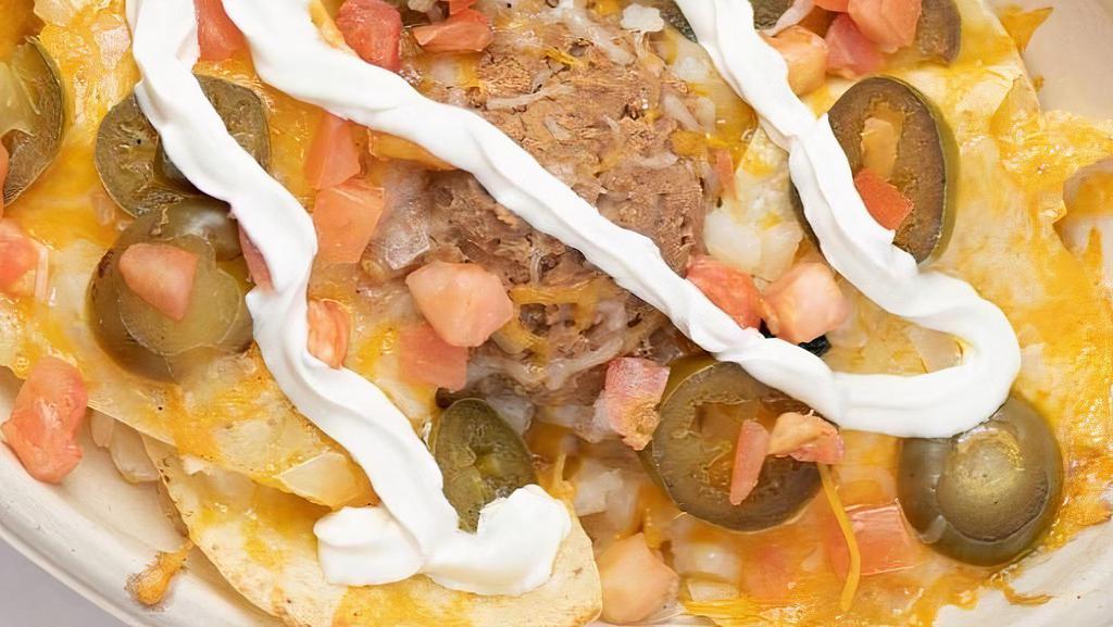 Nachos Deluxe · On a plate of fresh tortilla chips we melt cheese, and add refried beans, jalapeño peppers, onions, tomatoes, and sour cream.
