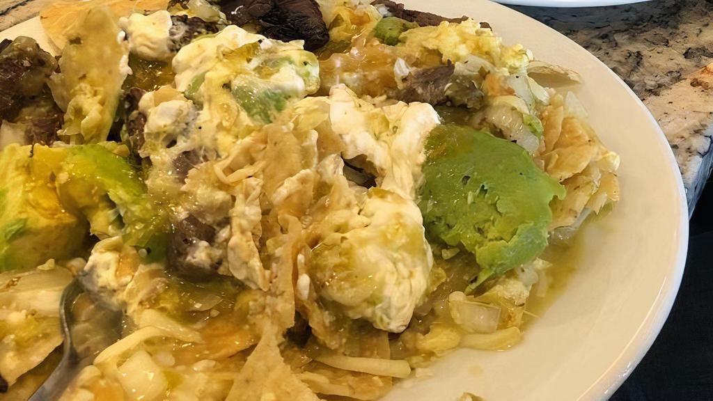 Chilaquiles · Tortilla chips tossed with melted mozzarella cheese, eggs and green salsa verde, topped with parmesan cheese and served with a side of salsa and sour cream.