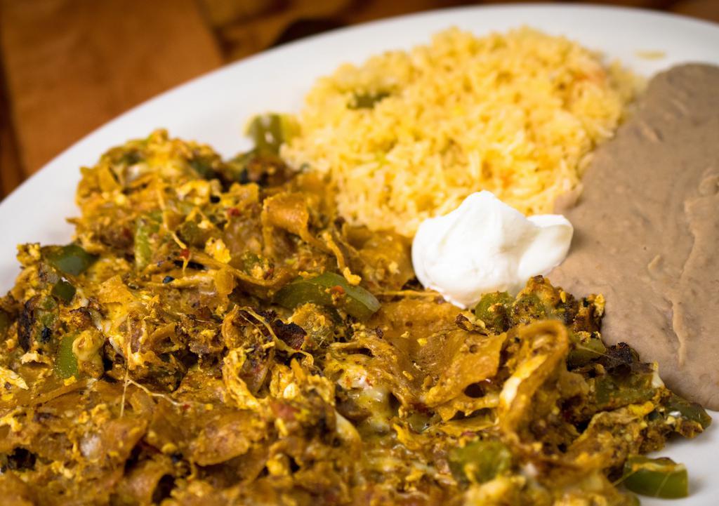 Chilaquiles · Corn chips cooked with green pepper, onion, tomato, Green or Red salsa, eggs and melted cheese. Served with rice, beans, sour cream, lettuce, tomato, and corn or flour tortillas.