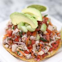 Fish Tostada · Fish ceviche on a corn tostada with slices of avocado.
