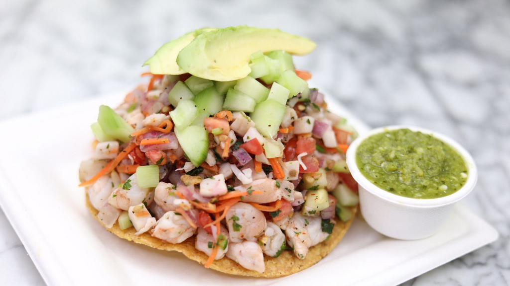 Mix Tostada · Fish and Shrimp Ceviche on a corn tostada with slices of avocado.