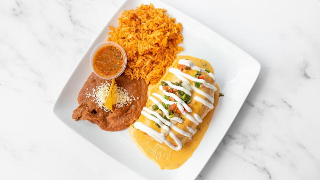 Calgary Chimichanga · Your choice of chicken or beef burrito and cheese deep-fried and topped with espinaca con queso sauce, sour cream and pico de gallo. Served with rice and beans.