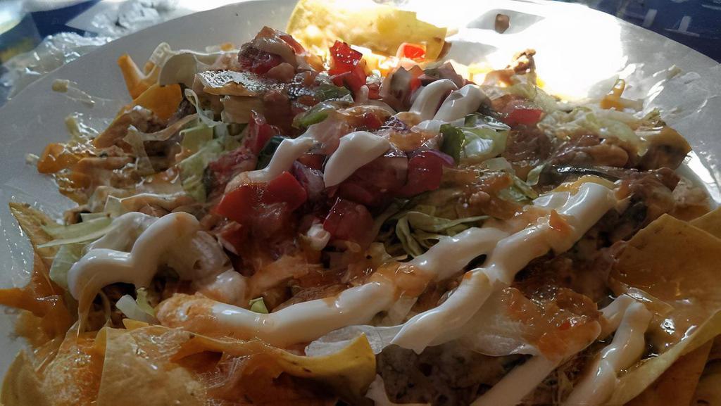 Nordique Nachos · Topped with refried pinto beans, pico de gallo, cheddar cheese, espinaca con queso cheese, lettuce, sour cream and side of house salsa. Your choice of chicken or ground beef (grass fed).
