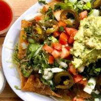 Nachos, Nachos, Nachos · Housemade tortilla chips smothered in Chihuahua cheese, guacamole, refried beans, diced toma...