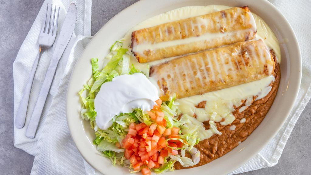 Chimichanga · Two fried burritos of your choice of shredded chicken, ground beef or shredded beef with beans, lettuce, guacamole, sour cream and tomato. Topped with melted cheese.