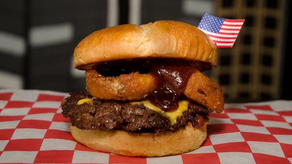 Rodeo Burger · Butter seared beef, melted American cheese, beer-battered onion rings, crispy bacon, and sweet BBQ, on toasted buns. All burgers are cooked well done.