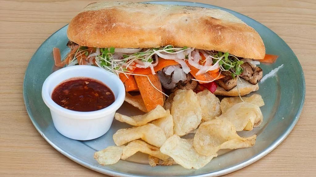 Tofu Banh Mi · Hot and fresh sandwich on an 8-inch toasted bun filled with seared tofu, grilled red bell pepper, scallion whites, bamboo, and marinated shiitake mushroom. Topped with cilantro, scallions, fresh ginger carrots and daikon. Served with chips.