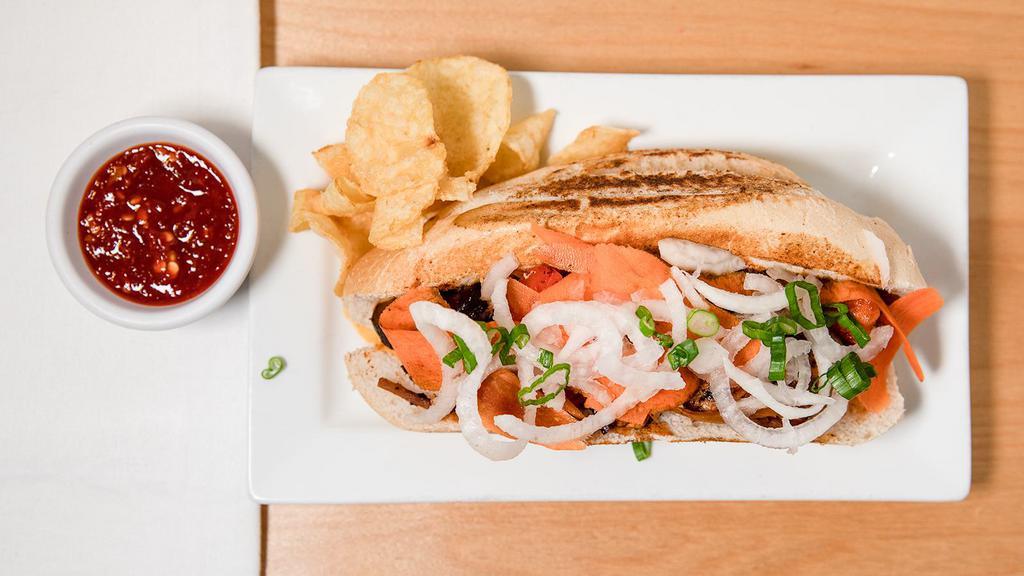 Chicken Banh Mi · Hot and fresh sandwich on an 8-inch toasted bun filled with free range chicken, grilled red bell pepper, scallion whites, bamboo, and marinated shiitake mushroom. Topped with cilantro, scallions, fresh ginger carrots and daikon. Served with chips.