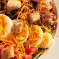 Cobb Salad · Crisp romaine and iceberg lettuce layered with diced tomatoes, turkey, bacon and egg, topped...