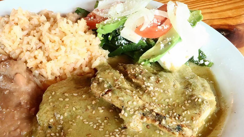 Mole Verde · Grilled chicken breasts coated with tomatillo sauce and served with rice, refried beans, corn tortillas, and a poblano pepper mix.