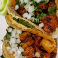 Tacos · Two soft corn tortillas, meat choice, cilantro, and onion, served with a side of rice.