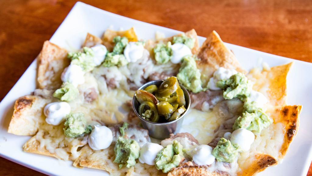 Nachos · Home-made tortilla chips individually layered with re-fried beans, melted cheese, guacamole, sour cream, and a side of jalapenos.