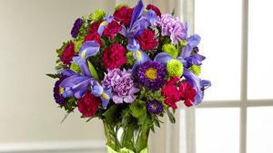The Ftd Share My World Bouquet · Share a world blooming in brilliant color and undeniable texture with this frilly and fun fresh flower bouquet . Blue iris, burgundy mini carnations, green button poms, lavender carnations, purple Matsumoto asters, lavender roses, and lush greens mingle together to create a fascinating display. Presented in a modern clear glass vase tied with a lime green satin ribbon at the neck, this gift of flowers is a special surprise your recipient will love. Good bouquet includes 11 stems. Approximately 15
