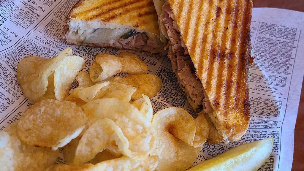 Cuban · Sourdough. Pork, ham, swiss cheese, onion, pickle, mayo, mustard. Served with a pickle and chips on bread. Substitute chips for a salad for an additional charge.