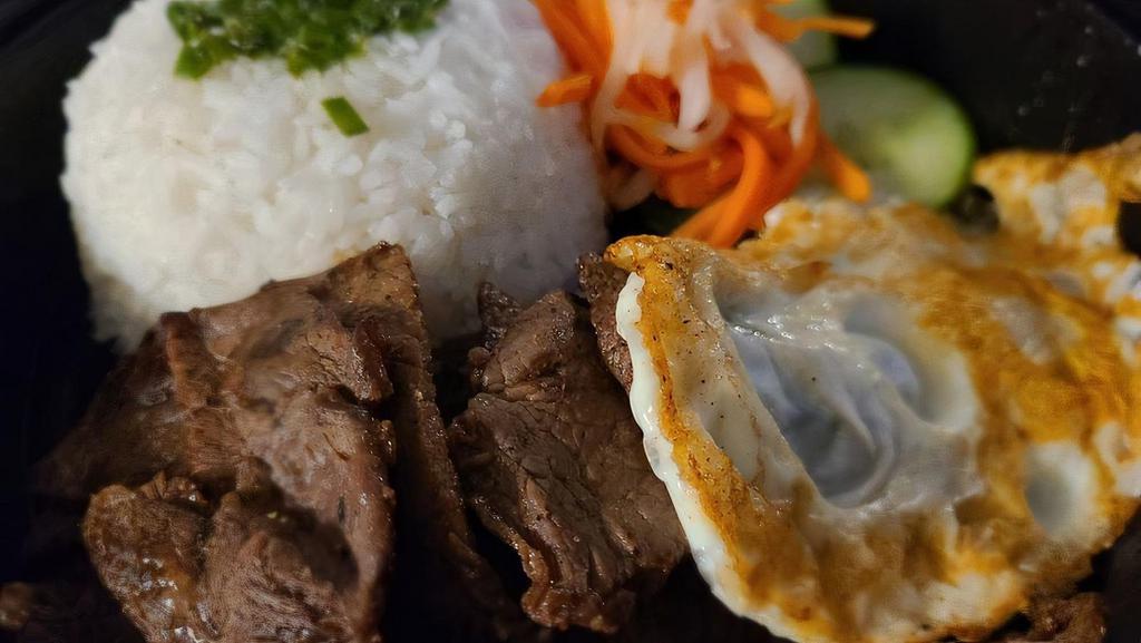 Rice With Grilled Protein · Your choice of marinated pork, beef, chicken, or crispy tofu plated with white rice, pickled cucumbers, daikon and carrots, and an over-medium egg. Topped with green onion and served with a bowl of Pho broth and our house-made jalapeño fish sauce.