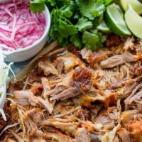 Cochinita · Slow roasted shredded pork cooked in a rich red guajillo salsa. Served with a side of black ...