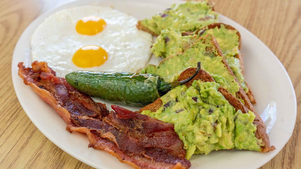 Avocado Toast · grilled whole wheat toast topped with smashed avocado with onions tomato served with two eggs cooked your way and two slices of bacon.