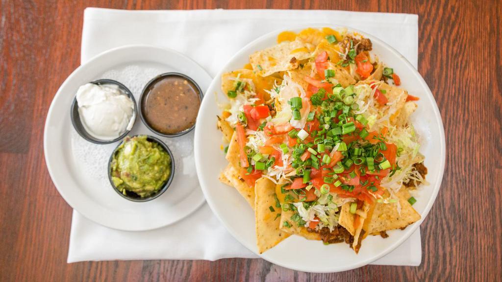 Nachos · fresh tortilla chips, seasoned beef, mexican cheese blend, pico de gallo and shredded lettuce, topped with sour cream, guacamole and salsa