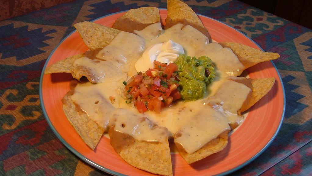 Nachos · Corn tortilla chips topped with refried beans and Mexican cheese. Served with fresh guacamole, sour cream and pico de gallo.