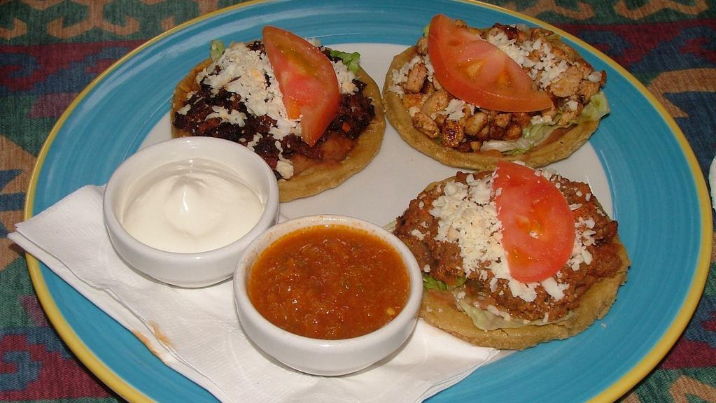 Sopes · Three ground beef, steak, chicken, shredded beef or seasoned pork sopes topped with beans, lettuce, tomatoes, and cheese. Accompanied with ranchera sauce and sour cream.
