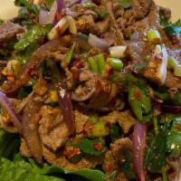 Nam Tok · Spicy. Broiled sliced beef mix with rice powder, onion, cilantro & chili in a lime dressing.