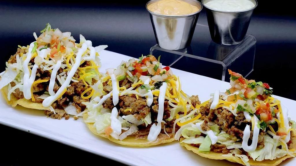 Tostadas · Three fried corn tortilla topped with refried beans, shredded lettuce, seasoned ground beef, monterrey jack & cheddar cheese, sour cream, and pico de gallo. Served with our Chipotle Crema and Green Sauce.