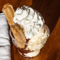 Churro Sundae · Vanilla ice cream sundae topped with choice of syrup with a churro cut in half.