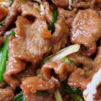 Mongolian Beef · Slices of beef with green onions stir fried overlaying a bed of rice stick noodles.