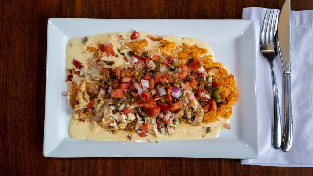 Smothered Chicken Dinner · Cajun seasoned chicken breast grilled with sautéed onions & peppers and corn succotash smothered with our white queso sauce mixed with pico de gallo served with Spanish rice.