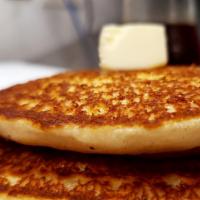 Buttery Pancakes · Two buttery pancakes topped with butter and a side of maple syrup
