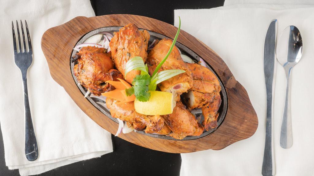 Tandoori Chicken · Whole tender spring chicken marinated in mild spices, fresh herbs, & cooked in the clay oven, served sizzling with grilled onions & lemon.