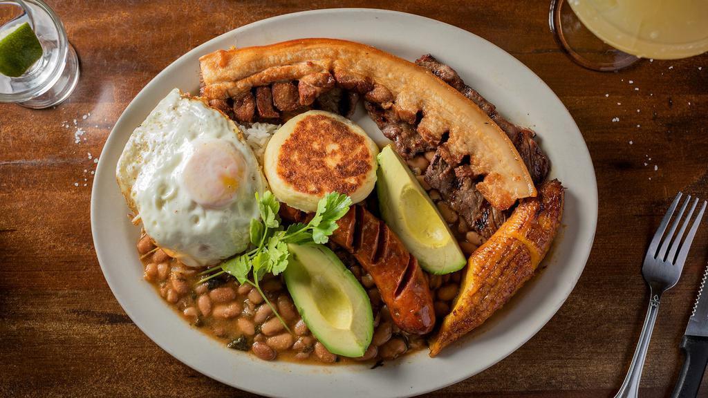 Bandeja Paisa · Char-broiled, colombian-style cut rib-eye steak served with fried pork belly, chorizo, rice, beans, fried egg, sweet plantain, and avocado.