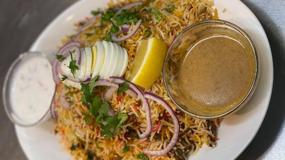 Hydrabadi Chicken Dum Biryani · Basmati rice cooked with tender pieces of chicken, blended with herbs and spice garnish with eggs, onions, and lemons.