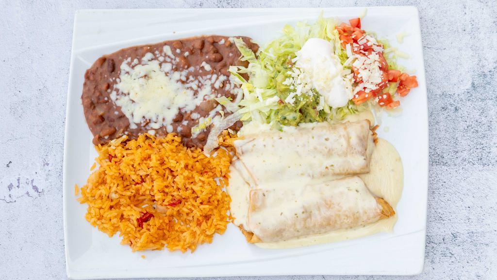 Chimichanga · Two flour tortillas, soft or deep fried, filled with shredded beef or chicken. Topped with lettuce, tomatoes, sour cream, nacho cheese and guacamole, served with rice, and beans.