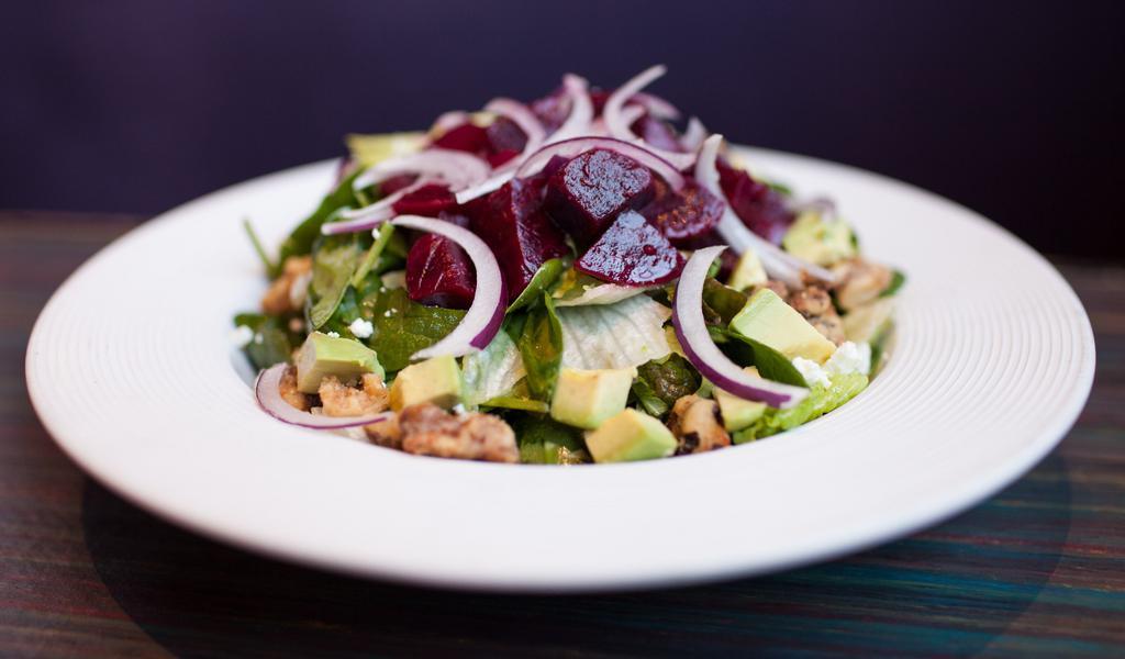 Beet Salad · A blend of leaf lettuce, spinach, avocado and fresh beetroot, tossed in our house champagne vinaigrette topped with goat cheese, candied walnuts and sliced red onion.