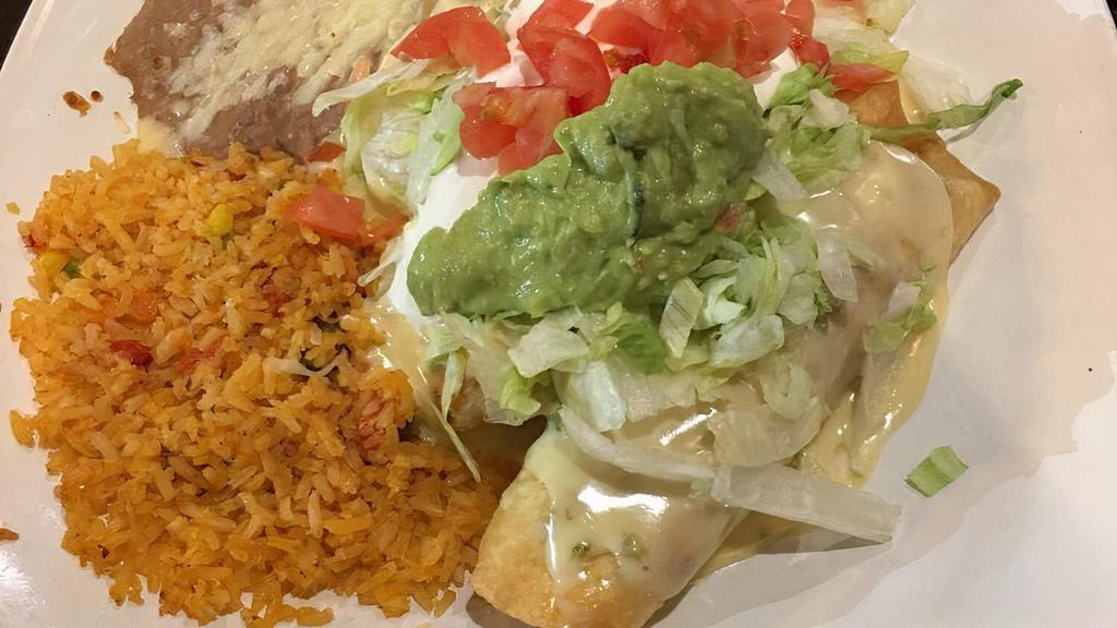 Chimichangas Supreme · Two flour tortillas rolled up and stuffed with shredded beef, pork or chicken, then covered with cheese sauce, served with rice and beans and guacamole salad.