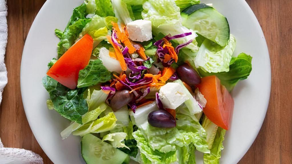 Greek Salad · A mixture of fresh romaine lettuce, tomatoes, cucumber, red onions, feta cheese and kalamata olives topped with our house dressing. Garnished with shredded carrots and red cabbage.