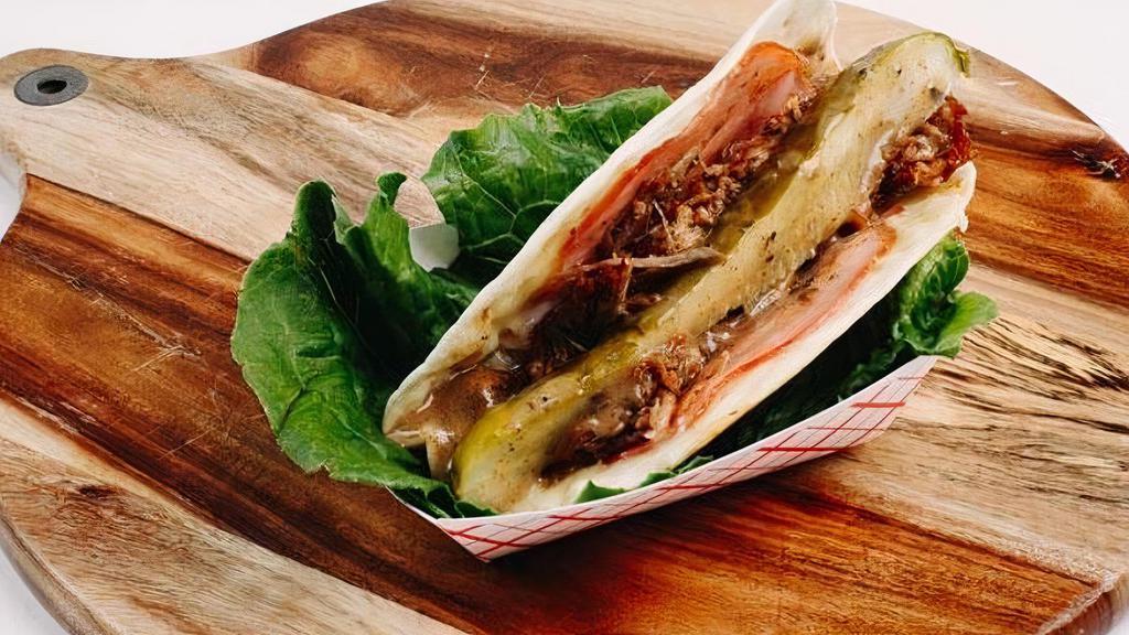 Cubano Taco. · Roasted pork, sliced ham and cheese, grilled together and served with pickle and Mojo sauce
